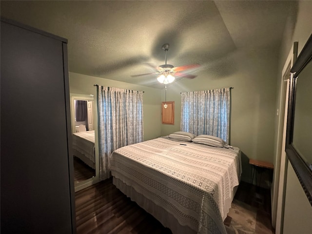 bedroom featuring dark wood-type flooring, ceiling fan, lofted ceiling, and a textured ceiling