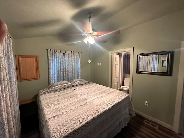 bedroom with ensuite bathroom, vaulted ceiling, dark wood-type flooring, ceiling fan, and a textured ceiling