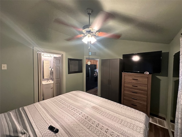 bedroom with ensuite bathroom, lofted ceiling, a closet, black fridge, and ceiling fan