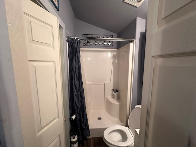 bathroom with lofted ceiling, walk in shower, toilet, and a textured ceiling