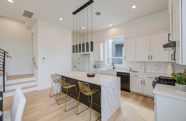 kitchen with white cabinets, dishwasher, a center island, light hardwood / wood-style floors, and hanging light fixtures