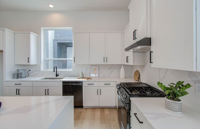 kitchen featuring black gas range oven, white cabinetry, stainless steel dishwasher, and light stone counters