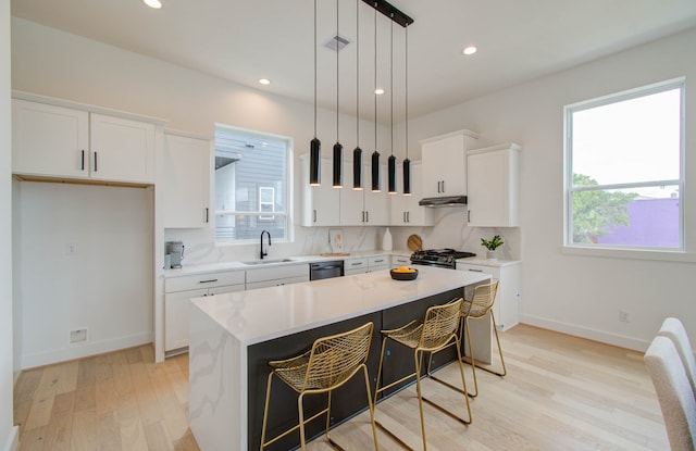 kitchen with white cabinets, decorative light fixtures, a kitchen island, and a healthy amount of sunlight