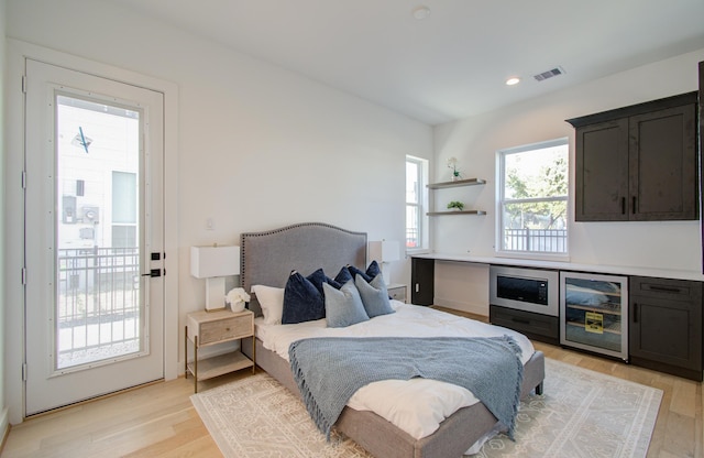 bedroom with access to exterior, beverage cooler, and light hardwood / wood-style flooring