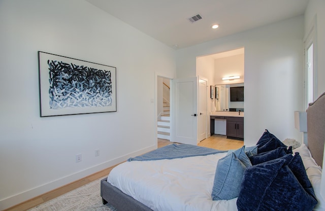 bedroom featuring connected bathroom and light hardwood / wood-style flooring