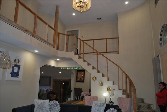 stairway with a towering ceiling and a notable chandelier