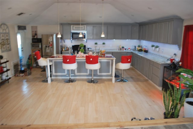 kitchen with a kitchen bar, pendant lighting, and gray cabinetry