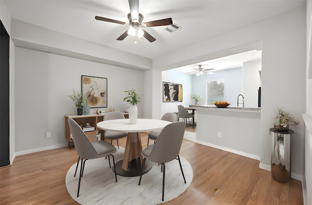 dining room featuring ceiling fan, sink, and light hardwood / wood-style flooring