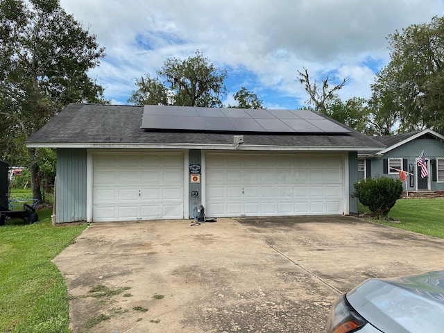 garage with a yard and solar panels