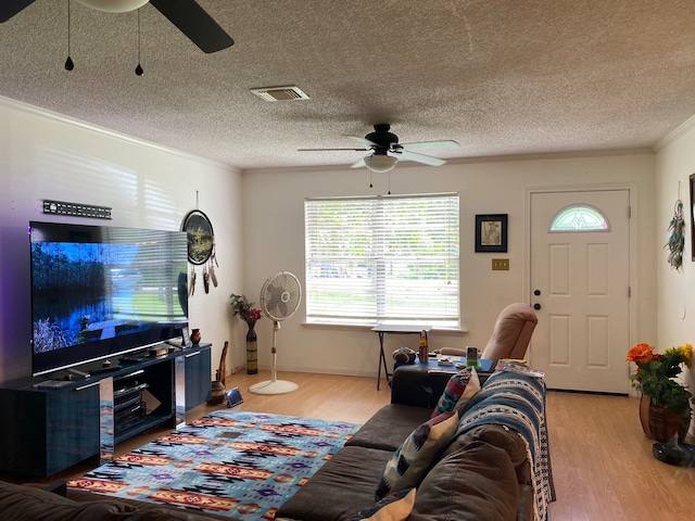 living room with light wood-type flooring, crown molding, a textured ceiling, and ceiling fan