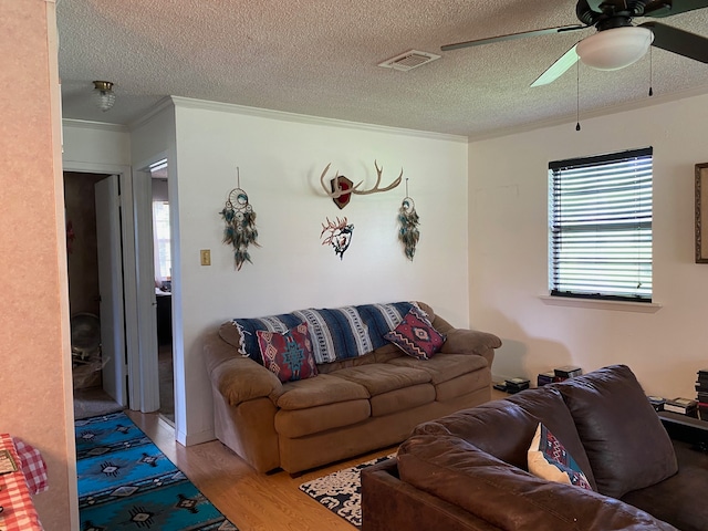 living room with ceiling fan, light hardwood / wood-style floors, crown molding, and a textured ceiling