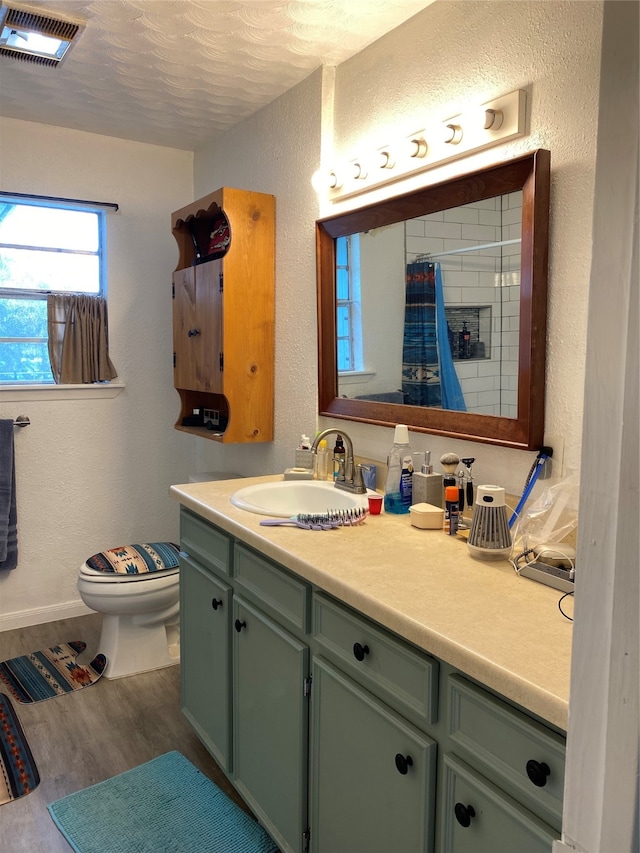 bathroom featuring a textured ceiling, vanity, walk in shower, toilet, and hardwood / wood-style flooring