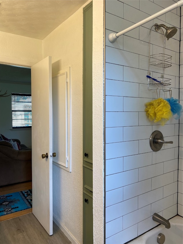 bathroom with tiled shower / bath and hardwood / wood-style floors