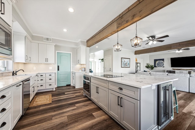 kitchen with white cabinetry, dark wood-type flooring, ceiling fan with notable chandelier, beam ceiling, and a spacious island