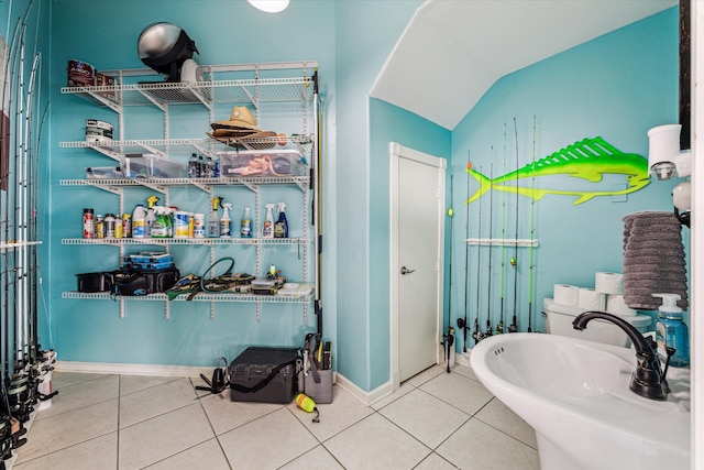 bathroom with vaulted ceiling, tile patterned floors, and sink