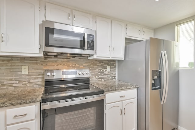 kitchen featuring appliances with stainless steel finishes, white cabinetry, a healthy amount of sunlight, and tasteful backsplash