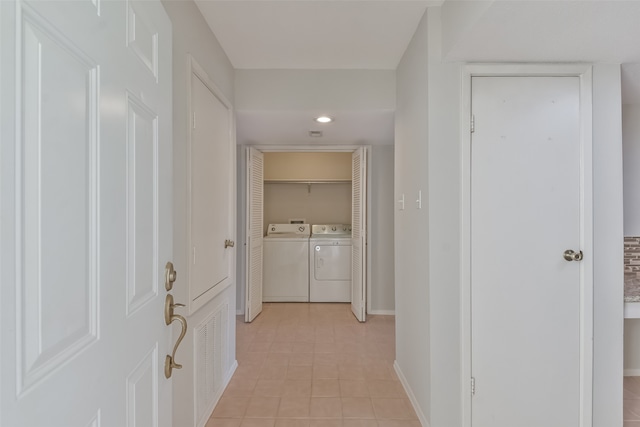 hallway with separate washer and dryer and light tile patterned flooring