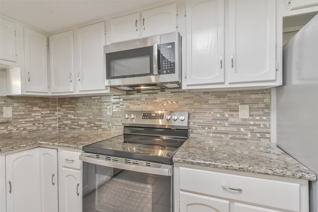 kitchen with stainless steel appliances, light stone counters, backsplash, and white cabinetry