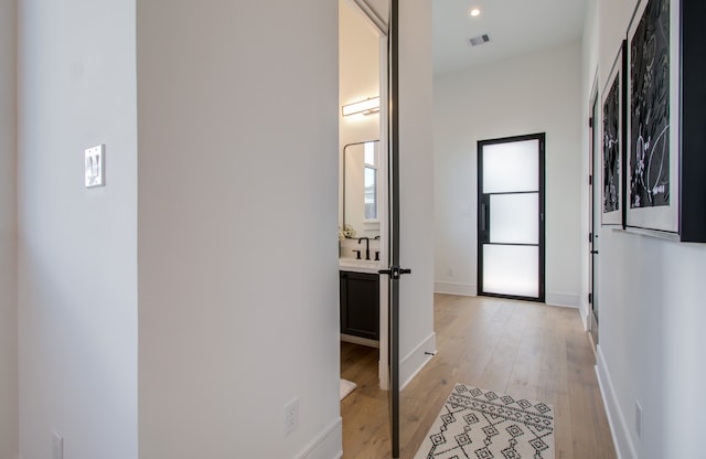 hallway with light wood-type flooring and sink