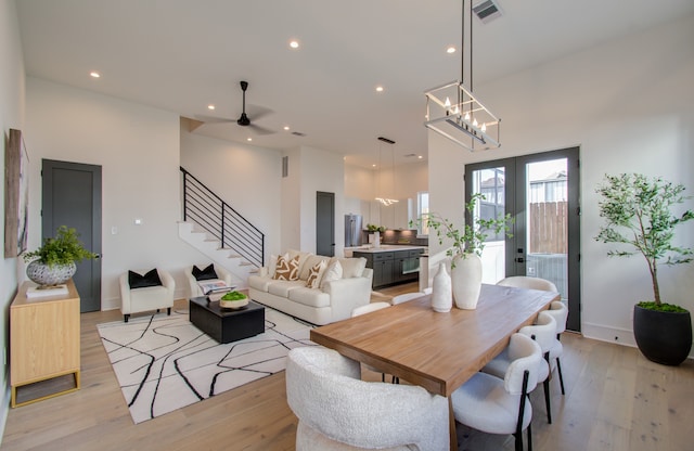 dining space featuring ceiling fan with notable chandelier, french doors, and light hardwood / wood-style floors