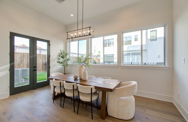 dining area featuring light hardwood / wood-style flooring, a notable chandelier, and french doors