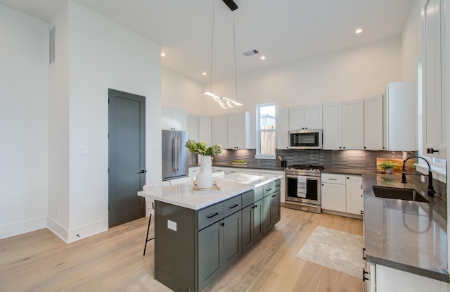 kitchen with hanging light fixtures, a center island, stainless steel appliances, sink, and a kitchen bar