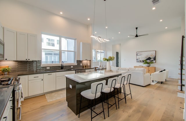 kitchen featuring ceiling fan, a center island, stainless steel appliances, and light hardwood / wood-style flooring