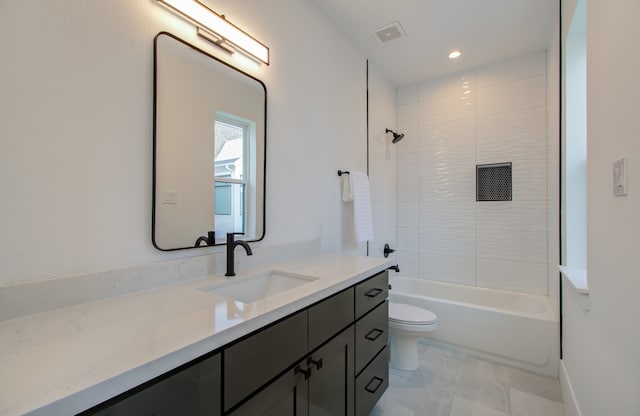 full bathroom featuring tiled shower / bath, vanity, and toilet