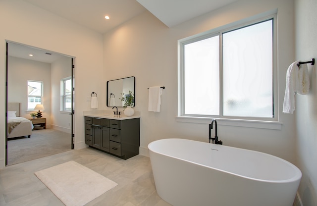 bathroom featuring a tub to relax in, vanity, and plenty of natural light