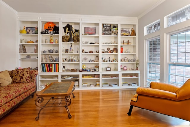 living area with wood-type flooring and ornamental molding