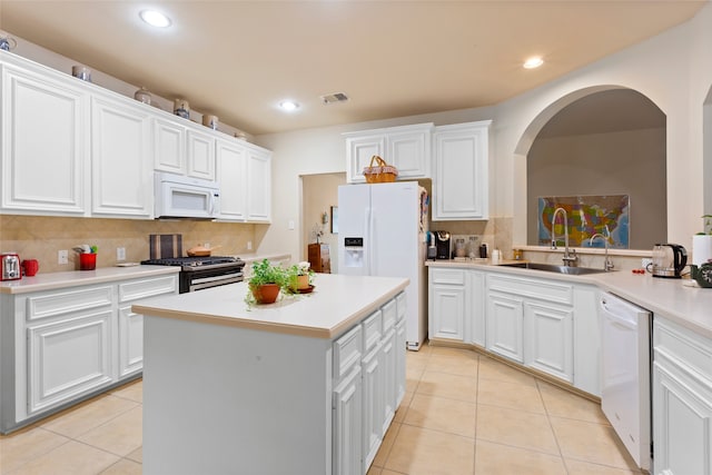 kitchen with decorative backsplash, white appliances, sink, white cabinets, and a kitchen island