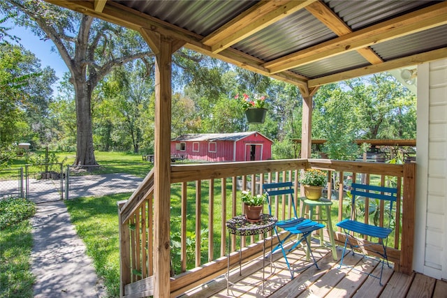 wooden terrace featuring an outbuilding, a gate, a storage unit, fence, and a yard