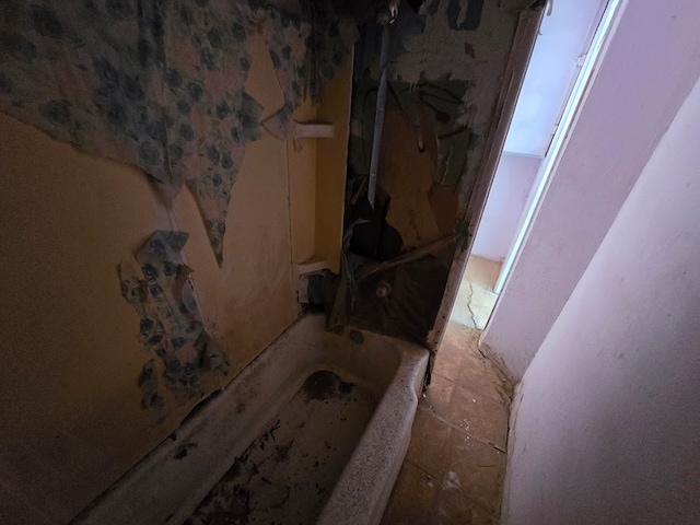 bathroom with a tub to relax in and tile patterned floors