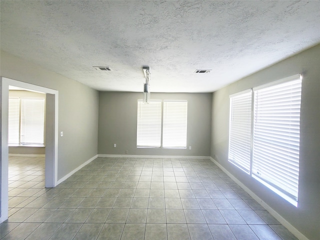 tiled empty room with a textured ceiling and a wealth of natural light