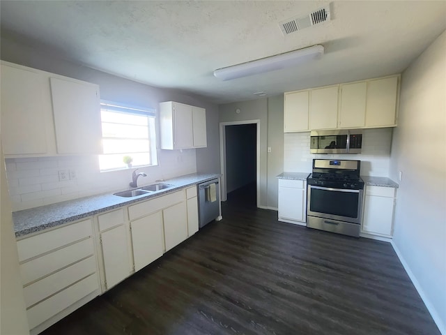 kitchen featuring dark wood-type flooring, appliances with stainless steel finishes, white cabinetry, and sink