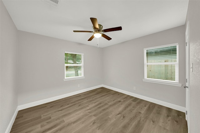 spare room with wood finished floors, baseboards, visible vents, and ceiling fan