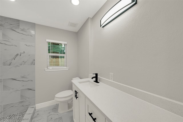 bathroom featuring toilet, vanity, and a tile shower