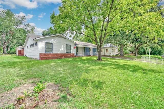 ranch-style home with a front yard, brick siding, and fence