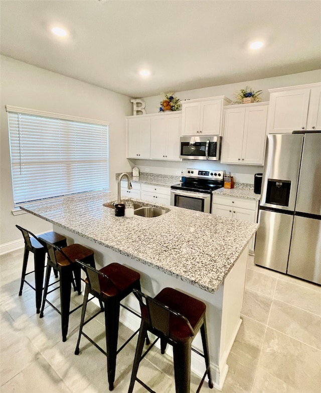 kitchen featuring appliances with stainless steel finishes, a kitchen breakfast bar, a kitchen island with sink, and sink