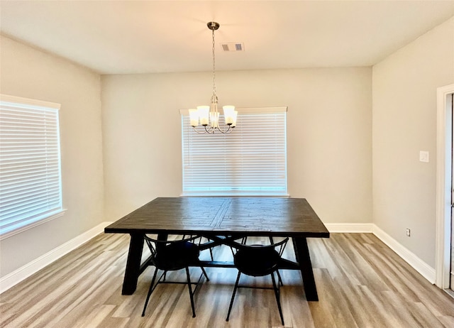 dining area with light wood-type flooring and a chandelier