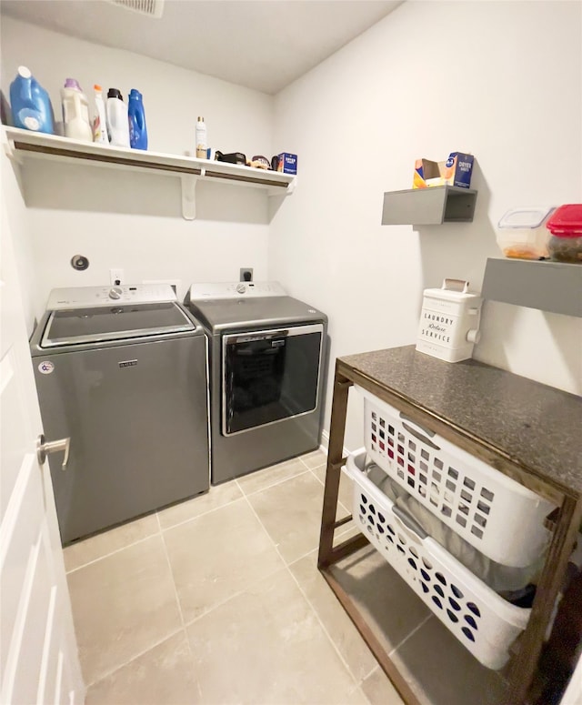 laundry area with independent washer and dryer and light tile patterned flooring