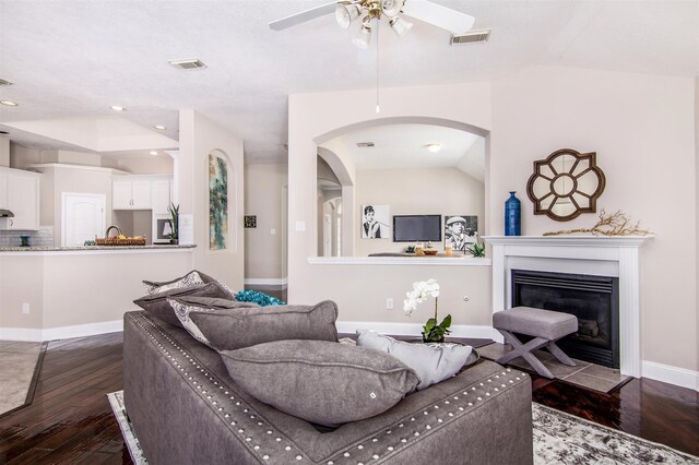 living room with dark wood-type flooring, ceiling fan, and vaulted ceiling