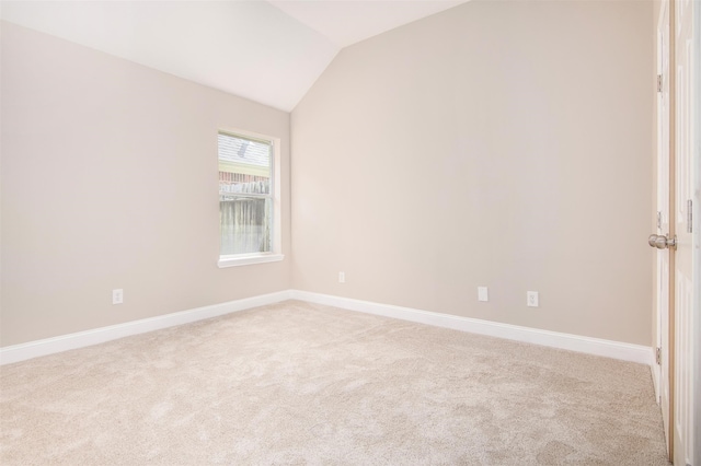 carpeted spare room featuring vaulted ceiling