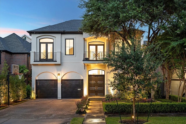 view of front of house featuring french doors, a balcony, and a garage