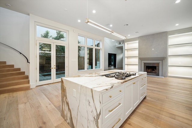 kitchen with light stone counters, white cabinetry, light hardwood / wood-style flooring, and a center island