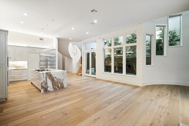 kitchen with decorative light fixtures, gray cabinetry, stainless steel built in fridge, light hardwood / wood-style floors, and light stone countertops