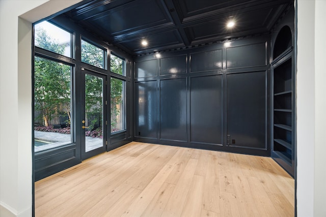 unfurnished room featuring light hardwood / wood-style flooring, built in features, beam ceiling, coffered ceiling, and ornamental molding