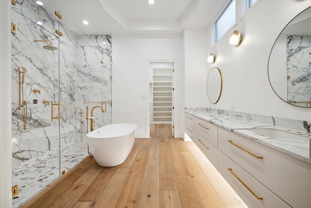 bathroom with a tray ceiling, vanity, hardwood / wood-style flooring, and shower with separate bathtub