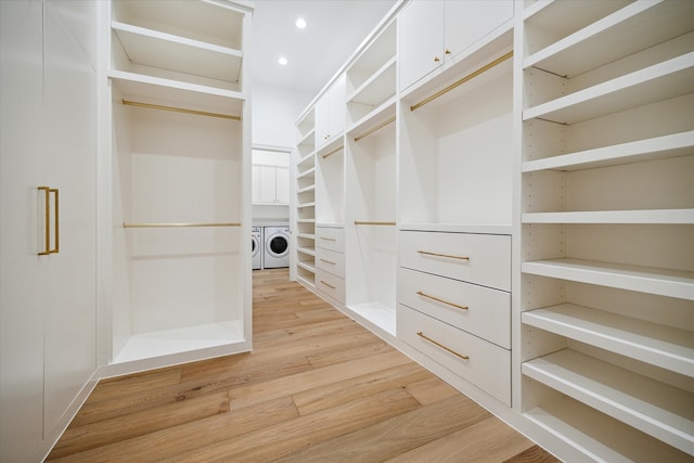 spacious closet featuring separate washer and dryer and light hardwood / wood-style flooring