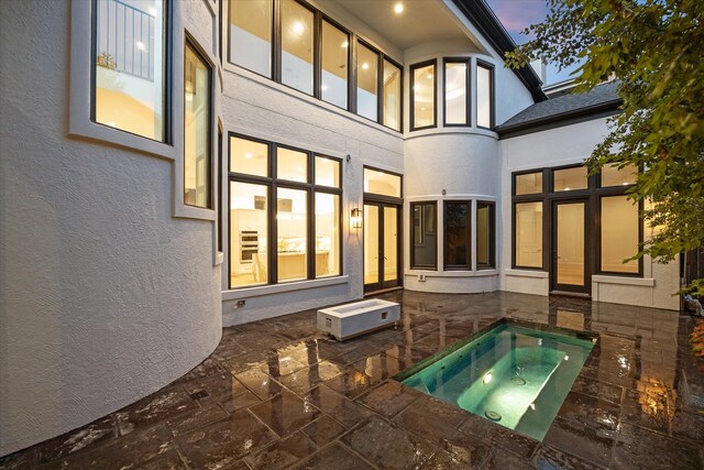 back house at dusk with a patio and an in ground hot tub